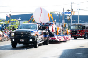 A truck towing a parade float with a giant baseball on it