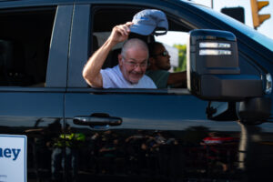 Parade float passenger tipping his cap to the crowd